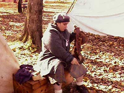 Here I am fixing one of Clann Tartan's bandoliers. A bandolier consists of a leather belt that hangs on your left shoulder, goes across your chest, and has a bag that hangs by your right hand. It then has twelve to fourteen little wooden bottles attatched to it that were used to hold a measured charge of blackpowder for the matchlock musket. Keeping the eqipment in good condition is very important, and it is one of my duties within the group.